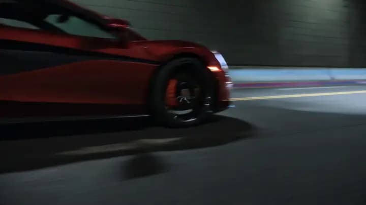 A red sports coupe racing out of a dark tunnel into wet city reflections in a cinematic automotive shot.